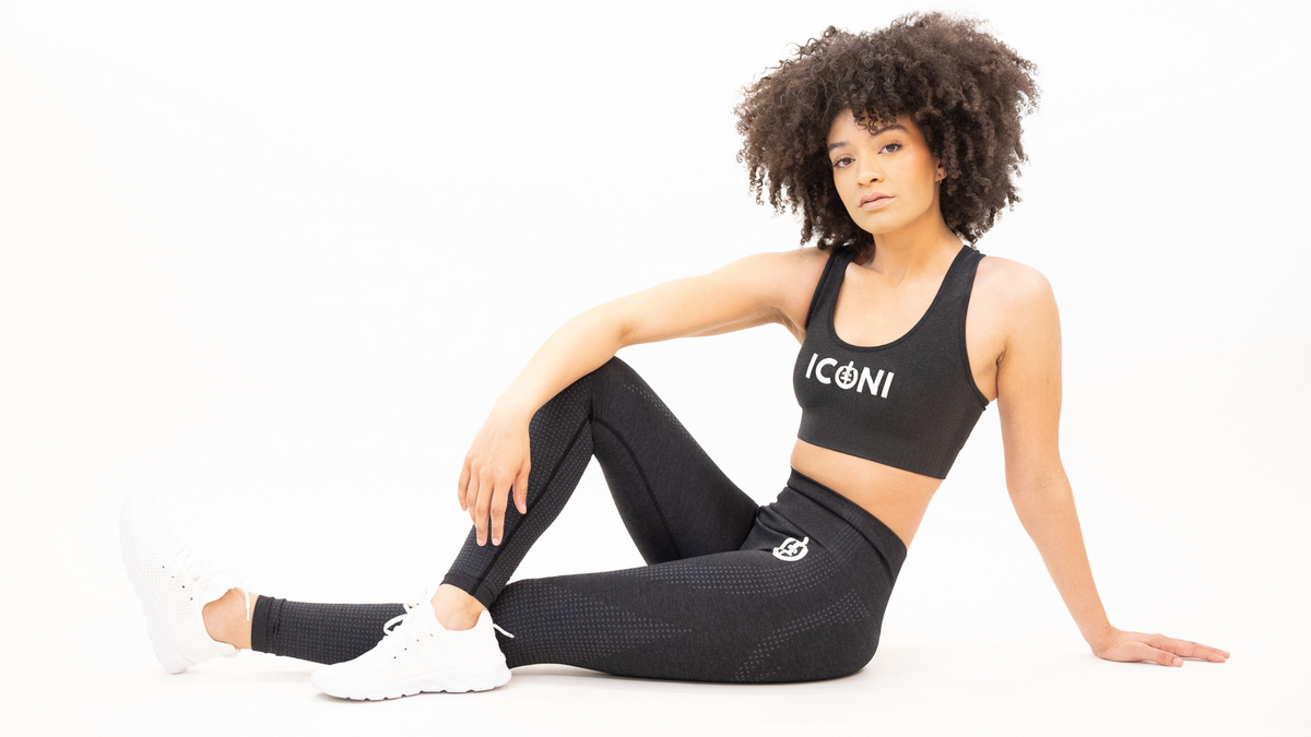 Woman in ICONI sports and legging sitting down on ground posing 