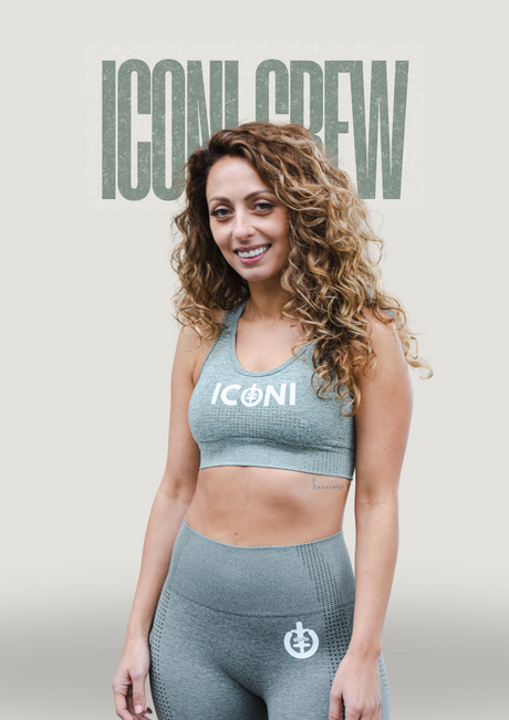 Women with long hair in ICONI optimistic olive sports bra and legging smiling with the words ICONI Crew behind her