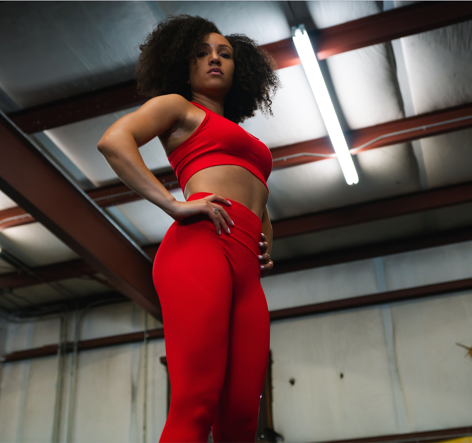 Woman wearing red ICONI sports bra and legging with her hands on her hips