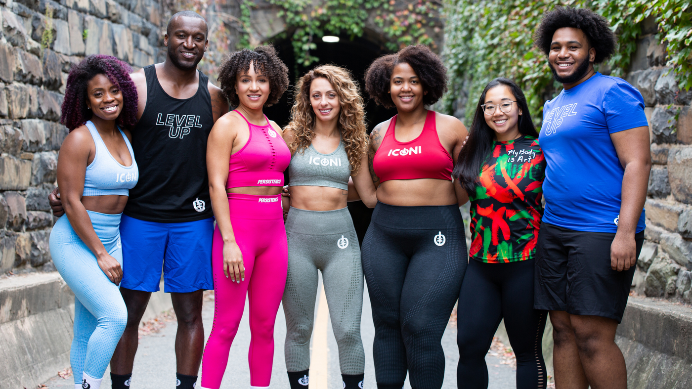 5 diverse women and 2 diverse men in ICONI activewear standing together as a group and smiling