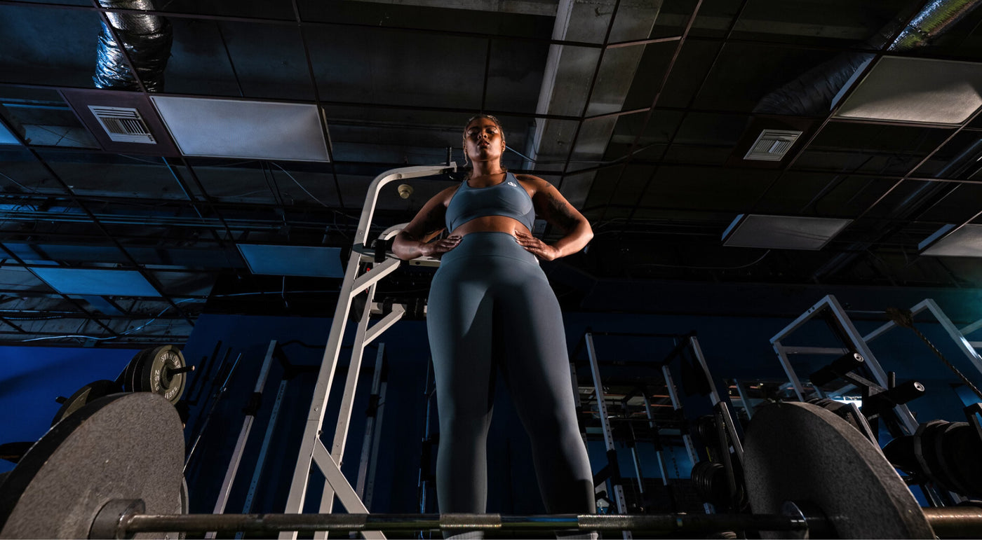 Woman wearing ICONI sports bra and legging standing confidently with hands on her hips in the gym